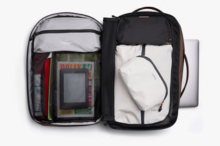 Open backpack with compartments containing books, a bag, and other items on a white background