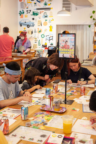 Group of children creating crafts at a long table with markers and drinks