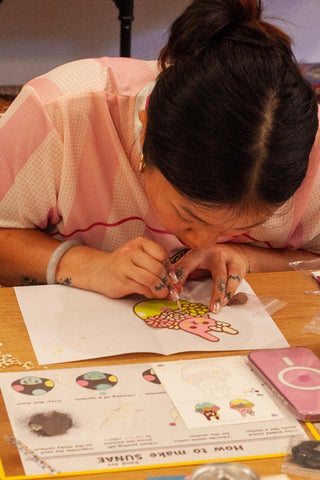 Child coloring on paper at a table with markers and colored pencils