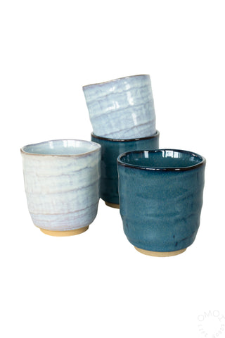 Four ceramic teacups glazed in light and dark blue on a white background