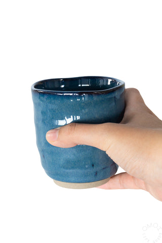 Kinyou dark blue ceramic teacup held in hand, glossy rim and textured surface