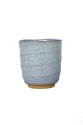 Front view of light blue ceramic glazed teacup on a white background