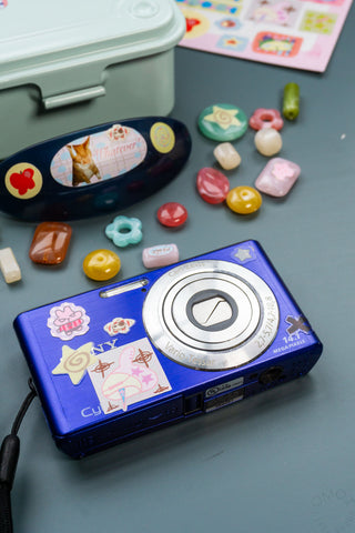 Blue camera with colorful beads on a blue background