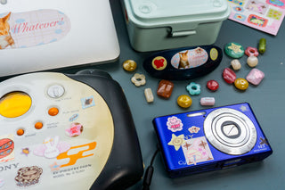 close up of vintage CD player and blue camera decorated with stickers on a blue background