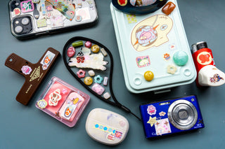 Collection of sticker decorated phone cases, toolbox, and camera on a blue surface