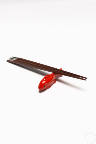 Red fish-shaped chopstick rest with dark chopsticks resting on top