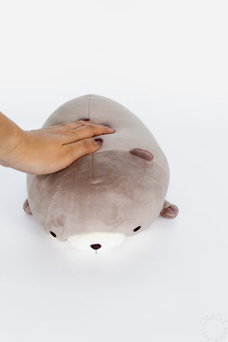 Hand on top of otter plush on a white background