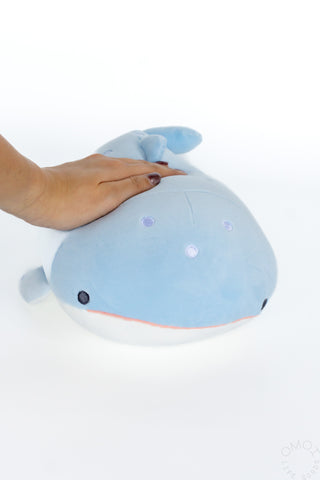 Blue whale shark plush on a white background with hand on top