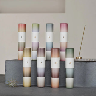 Set of gradient incense tubes in varied colors with bundled sticks and one burning stick