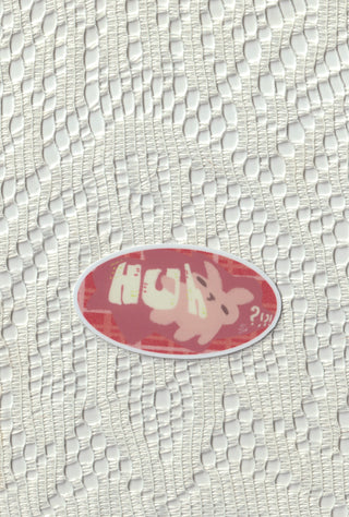 Oval die cut sticker with Huh?! text and a bunny on a lace background