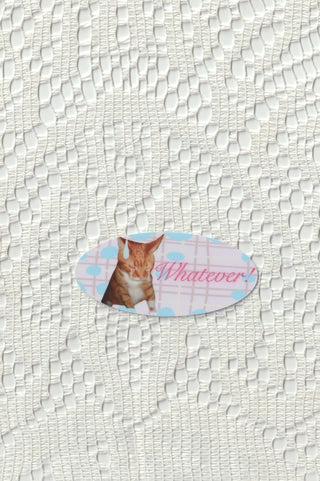 Oval die cut cat sticker with Whatever! text on a lace background