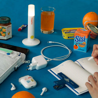 Assorted items including a glass of juice, notebook, and electronic devices on a blue surface.