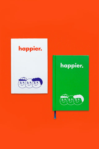 Two 'happier.' notebooks, one white and one green, on an orange background.