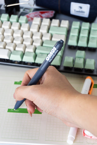 Hand holding zento pen over a desk calendar with a keyboard in the background
