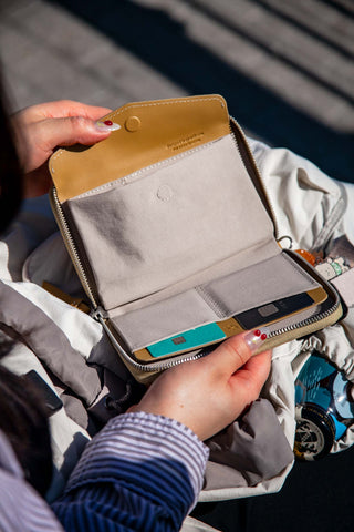 Person holding a small open bag with a cards inside, surrounded by clothes.