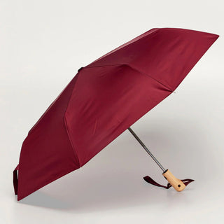 Maroon umbrella with a wooden handle on a light gray background