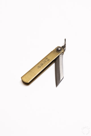 Mini pocket knife with brass handle, blade extended and visible near pivot