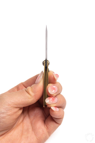 Mini pocket knife held in hand, small blade extended from brass handle