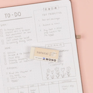 Planner with to-do list and priority tasks on a pink surface, featuring an eraser labeled 'natural mono'.