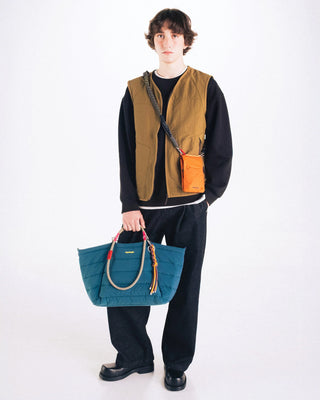 Person holding a blue bag with straps on a white background