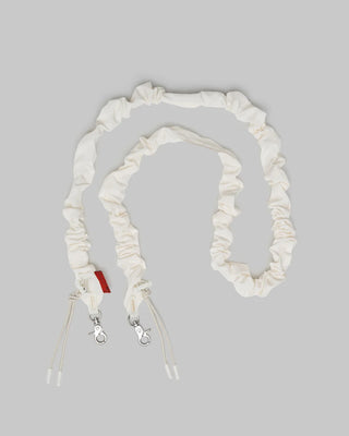 White ruched strap with red tag on gray background