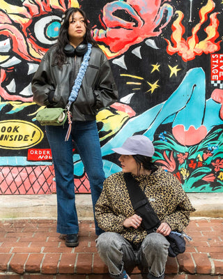 Two people pose before a colorful street mural