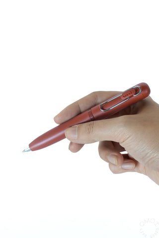 Brick red multi-color gel pen held in a hand, metal tip visible