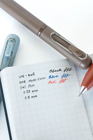 Brick red multi-color gel pen beside a lined notebook page