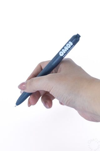 Hand holding OMOI Zento pen on a white background