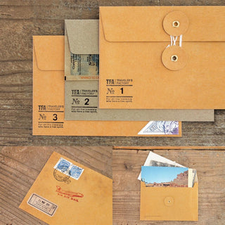 Set of orange kraft envelopes with eyelet closures and travel-themed inserts