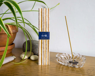Pack of sandalwood incense sticks with striped wrapper and blue band, standing upright