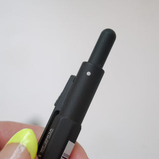 Matte black multi-pen close-up of clip and side switch on textured body