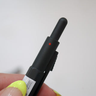 Matte black multi-pen with red dot indicator on the grip area, close-up