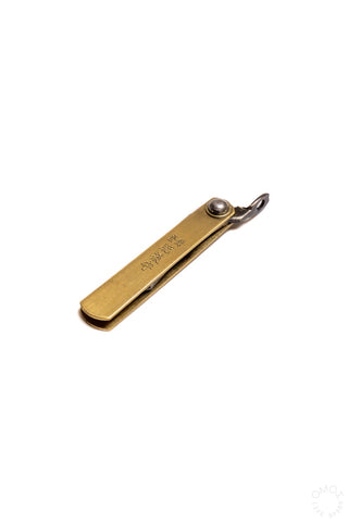 Mini pocket knife lying flat, brass handle with blade folded near pivot